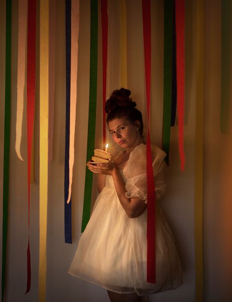 A girl in a fluffy white dress stands amidst birthday streamers holding a cake with a lit candle Retro Birthday Photoshoot, Fun Birthday Photoshoot Ideas, Vintage Birthday Photoshoot, Photoshoot Birthday Ideas, Birthday Self Portrait, Themed Photoshoot Ideas, Event Photography Ideas, Photography Campaign, Birthday Streamers