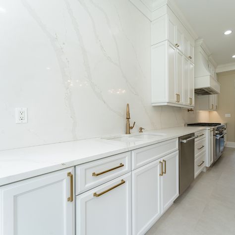 Full wall backsplashes are made to harmonize the countertops and backsplash with the entirety of the kitchen. Just look at that perfect symphony of whites and gentle marble-looking veining -- so elegant and beautiful! 🌿 

Contact us today for your quartz countertops + quartz backsplash combo. 🙌 

#howwedwell #kitchendesign #whitecabinets #kitchenmakeover #standoutstyling
#kitchenenvy #smmakelifebeautiful #thedelightofdecor #dailydecordose #whiteandgold #customkitchen #quartzbacksplash Solid Marble Backsplash Kitchen, Kitchens With Marble Backsplash, Full Height Backsplash Quartz, Backsplash Kitchen Quartz, White Marble Backsplash Kitchen, Full Wall Backsplash, White Marble Kitchen Backsplash, Kitchen Quartz Backsplash, Quartz Backsplash Kitchen