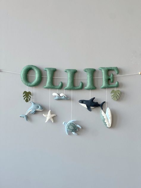 "Are you looking for a special and unique present for your loved ones? How about a baby name garland? A personalized safari name banner is the sweetest addition to any space in your home or given as a new baby gift. This personalized baby name sign will add the perfect finishing touch to your baby boy nursery, at a safari birthday party, or as a decorative accessory for photo props. INCLUDES Please select the number of letters in the name from the dropdown menu. Banner includes: ● letters, ● One main item per one letter. Please specify the main items (bear, fox, hare, deer, owl, tree) in the personalization window. ● additional items: leaves, triangles, little foil stars, clouds We will send you a photo before shipping =) This item made by hand - no machines involved. We hand-cut, hand-sew Otter Themed Nursery, Baby Boy Ocean Theme Nursery, Felt Nursery Decor, Beach Boy Nursery, Above Crib Decor Boy, Nursery Sea Theme, Under The Sea Nursery Boy, Coastal Nursery Neutral, Ocean Nursery Baby Boy