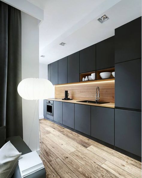 a black kitchen is made more interesting with a light-colored wood backsplash and an aged wood floor Dapur Ikea, Wood Kitchen Backsplash, Black Kitchen Design, New Kitchen Cabinets, Kitchen Cabinets Makeover, Trendy Kitchen, Kitchen Remodel Idea, Black Kitchens, Basement Remodeling