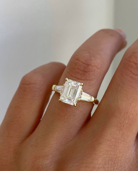 Emerald Cut Moissanite Engagement Ring, Accents Tapered Baguette, Solid Gold Three Stone Wedding Ring, Vintage Promise Ring, Gifts For Women ❤ ITEM DETAILS:- ✦ Brand: TheAmericanJewelShop ✦ Handmade, high-quality item! ✦ Material: Solid 10K/14K/18K Gold, 950 Platinum and 925 Sterling Silver ✦ Diamonds Type: Colorless Moissanite Diamond ✦ Diamond Cut: Emerald Cut ✦ Center Diamond Weight: 2.45 CT ✦ Center Diamond Size: 7x9 Mm ✦ Diamond Clarity: VVS/VS ✦ Width of Band: 1.8 Mm (Bottom) ❤ SIDE STONE:- ✦ 2 X 0.15 CT Tapered Baguette ----------------------------------------------------------------- 💎 Moissanite VS Diamond 💎 ------------------------------------------------------------------------------ 👉 Moissanite Maintain Their Clarity & Sparkle Throughout A Lifetime Just Like A Diamond. 👉Mo Engagement Rings Tapered Baguette, 3 Baguette Diamond Ring, Engagement Rings Emerald Cut Three Stone, Trio Emerald Cut Engagement Ring, Emerald Cut Engagement Ring With Baggets, Emerald Ring With Baguettes, Engagement Rings Baguette Side Stones, Trilogy Emerald Engagement Ring, Emerald Engagement Ring 3 Stone