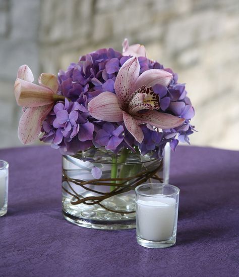 Small cylinder w/purple hydrangea, pink orchid, and grapevine accent Small Purple Flower Arrangements, Cocktail Table Arrangement, Wedding Cocktail Tables, Purple Flower Arrangements, Hydrangea Pink, Pink Flower Arrangements, Table Floral Arrangements, Small Purple Flowers, First Communion Party