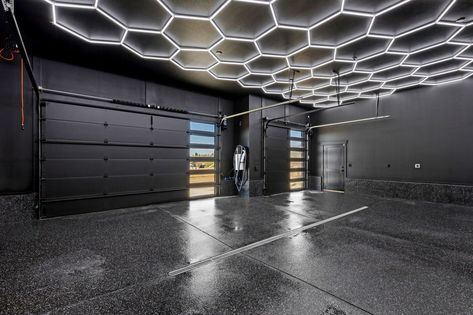 Hex lighting and black finished flooring complete this garage. High End Garage Design, All Black Garage Interior, All Black Garage, Black Garage Interior, Large Garage Ideas, Cozy Modern Home, Kitchen Cozy, Black Garage, Garage Design Interior