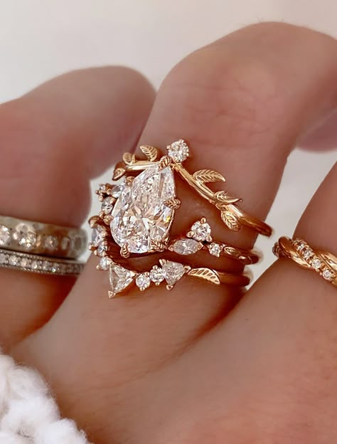 Harmony is a whimsical rose gold engagement ring that embodies the perfect balance of nature-inspired elegance and vintage charm. Our Adelixa acts as her leafy crown with a pop of sparkle. Kya completes this stack with her collection of trillion and round cut diamonds, and a dainty leaf engraving sits on either side to tie in an element of nature. Drop-down diamond options represent our recommended grade, which maximizes size for value, while maintaining eye-perfect clarity and giving you a colorless look. For other diamond options, see our Shop Diamonds tab or speak to one of our design consultants. This design can also be made with other stone shapes. Rings in this set can be purchased separately by visiting the individual product pages. Harmony's setting only cost: 14k Rose, White, or Y Pear Shaped Engagement Rings Unique, Dream Wedding Ring Rose Gold, Rose Quarts Engagement Ring, Vintage Wedding Rings Set, Rose Gold Wedding Ring Stack, Vintage Ring Designs, Heart Shape Ring Design Gold, Vintage Engagement Ring Set, Mexican Engagement Ring