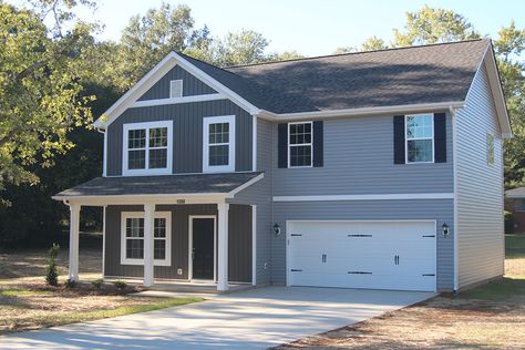 Vertical siding on the front elevation of this two-story house plan guides your eye upward to the cross-gable roof, while a covered porch welcomes you home.A coat closet in the entryway awaits your outdoor gear, and the adjoining living room provides forward-facing views. The main-floor powder bath is tucked beneath the stairwell, making good use of the space.The eat-in kitchen is located towards the rear, and offers access to a back patio, while the double garage connects to the kitchen ... House With Front Porch, Split Level Exterior, House Plans 2 Story, Moore House, Narrow Lot House, Vertical Siding, Two Story House Plans, Two Story House, 4 Bedroom House Plans