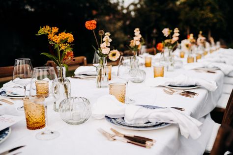 Garden Wedding with Orange and Yellow Flower Stems in Glass Bottles Simple Floral Wedding Table Decor, Coloured Glass Wedding Table, Wedding Table Single Flowers, Small Table Flowers Wedding, Eclectic Table Decor, Outdoor Garden Party Wedding, Forrest Weddings Decoration, Minimalistic Wedding Table Decor, Minimalist Wedding Table Setting