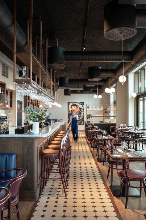 Bistro Le Bleu in Aarhus, Denmark has an airy and light interior design with large windows and a high ceiling. To ensure the bistro’s good acoustic qualities, black Troldtekt acoustic panels were chosen for the entire ceiling to camouflage the black-painted ventilation pipes and similar installations. #goodacoustics #holzwolleplatten #träullsplattor #woodwoolpanels #troldtekt | Architects: SLETH High Ceiling Cafe Design, Large Cafe Interior, Brasserie Design Interior, Modern Bistro Interior Design, Pizzeria Interior Design Ideas, Exposed Ceiling Design Restaurant, Bistro Interior Design Ideas, Bistro Bar Design, Low Ceiling Restaurant