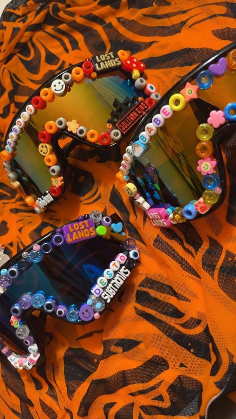 Custom Rave Glasses! Three different shades of glasses and custom beads. Completely customizable with bead colors and artist names. Artist we have are -Sullivan King -LSDream -Subtronics -Kai Wachi -Lost Lands And more to come! Subtronics Outfit, Kandi Glasses, Diy Rave Accessories, Totem Rave, Kandi Sunglasses, Rave Candies, Rave Gifts, Rave Totem Ideas, Rave Gift Ideas