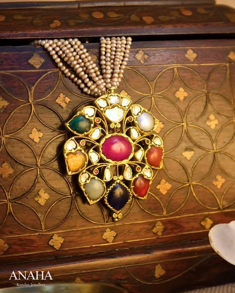 The classic Navratan pendant, featuring the nine gemstones symbolizing the planets, is believed to bring prosperity, health, and protection. At the heart of this piece, a radiant ruby represents the sun, encircled by the other planetary gems: Pearl (Moon), Red Coral (Mars), Emerald (Mercury), Yellow Sapphire (Jupiter), Diamond (Venus), Blue Sapphire (Saturn), Hessonite (Rahu), and Cat’s Eye (Ketu). What makes this pendant truly exceptional is the outward-opening petal design, stylized with de...