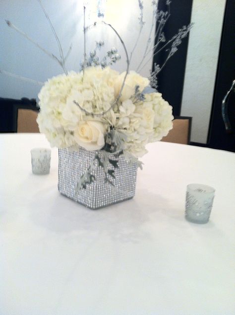 Winter centerpiece, all white flowers with silver accents, silver branches, rhinestone wrapped vase centerpiece Silver Centerpiece Wedding, Silver And White Centerpieces, White Silver Centerpieces, Silver Centerpieces, Silver Wedding Centerpieces, Round Table Centerpieces, All White Flowers, Anniversary Centerpieces, Winter Centerpiece