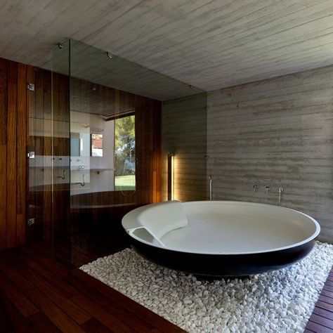 Circle shaped free standing tub surrounded by white stones.  The stones are a great contrast among the entirely wooden floors and walls. The white brick wall on the side also gives a good accent to the design. Bathtub Design, Skiathos, Interiors Dream, Bad Design, Dream Bathrooms, Dream Bathroom, Bath Tub, Beautiful Bathrooms, Amazing Bathrooms