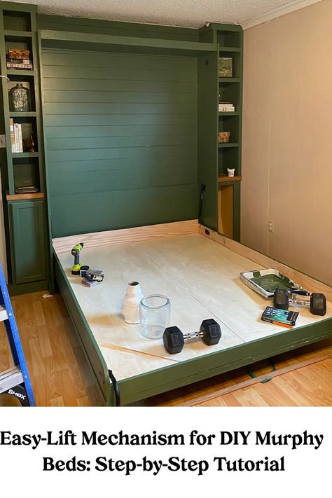 Easy-Lift Mechanism for a DIY Murphy bed in a home setup with weightlifting equipment and tools on the bed frame. Murphy Bed Measurements, Murphy Bed And Playroom, Bed That Goes Into Wall, Flex Room With Murphy Bed, Murphy Bed Dit, Craft Room Ideas With Murphy Bed, Bed On Wall Ideas, Murphy Beds For Small Spaces Bedroom, Bonus Room Murphy Bed