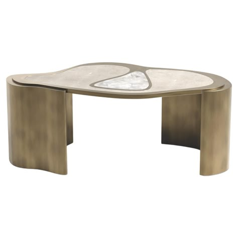 The Mask Coffee Table by Kifu Paris is a versatile and organic piece. The amorphous top and base are inlaid in a mixture of cream shagreen, white quartz and bronze-patina brass. This piece is designed by Kifu Augousti the daughter of Ria and Yiouri Augousti. Available in other finishes and as a nesting side table and a console table The finish of the shagreen is authentic as it is hand-dyed and the designer calls the finish look: "antique natural shagreen" The dimensions of this piece are 104 x 58.2 x 40 cm All Kifu Paris pieces are handmade by artisans, ultimately making each piece unique. Custom color/sizing available on request. Wipe clean with soft dry cloth. Although inspired by her parents, her collection of Home Accessories and Furniture is a distinct identity of its own. Kifu uses Kifu Paris, Shagreen Coffee Table, Antique Coffee Table, Bronze Patina, Coffee And Cocktail Tables, Table Centers, White Quartz, Center Table, Tea Table