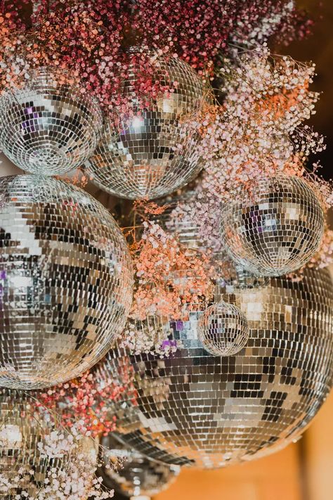 Custom made hanging installation for wedding dance floor with sprays of colorful small blooms and varying sizes of mirrored disco balls.