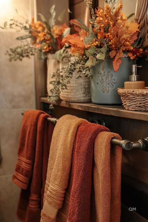 Cozy fall bathroom decor with warm-toned towels and vibrant autumn flowers in rustic containers. Perfect fall bathroom decoration ideas for your home. Bathrooms Decorated For Fall, Whimsy Bathroom Decor, Bathroom Decor Earth Tones, Fall Aesthetic Bathroom, Cozy Fall Decor Bathroom, Blue Fall Bathroom Decor, Fall Decor In Bathroom, Burnt Orange And Green Bathroom, Rust And Blue Bathroom