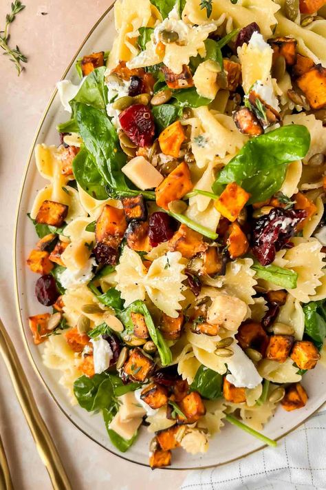 "Looking for a 30 minute recipe that is clutch for Thanksgiving, Friendsgiving, or Christmas? This is it. A fall salad loaded with roasted sweet potatoes, dried cranberries, sharp cheddar cheese, and bow-tie pasta. It feels like comfort food, without the heaviness of typical holiday foods. This easy fall harvest pasta salad convinced my fiance that ‘spinach actually is good’ – and that’s a mic drop for the delicious Maple vinaigrette dressing that coats this perfect fall salad. The Harvest Pasta Salad, Maple Vinaigrette Dressing, Fall Pasta Salad, Harvest Pasta, Fall Pasta, Maple Vinaigrette, Fall Salad, Thanksgiving Friendsgiving, Sweet Potato Spinach