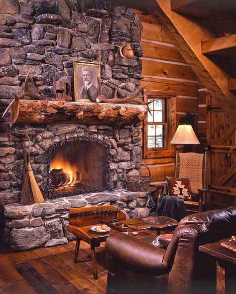 They wanted the cabin to look old and authentic but to have all of the comforts of home, too. Hanna’s friend and homebuilder Randy Baker says, “We hid the TV, refrigerator, dishwasher and all the electrical work behind custom panels designed to match the cabinetry.” Log Cabin Fireplace, Stone Fireplace Designs, River Rock Fireplaces, Cabin Fireplace, Fireplace Pictures, Log Cabin Living, Cozy Log Cabin, Log Cabin Ideas, Rock Fireplaces