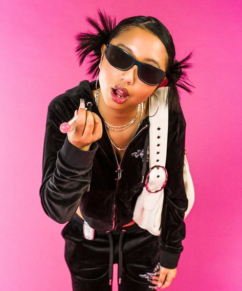 Girl standing in front of a pink backdrop leaning slightly forward, she has a sassy facial expression and is pointing at the camera holding a lollipop. She is wearing a black juicy couture tracksuit set, sunglasses and has a white shoulder bag over her left arm. The shoot is a y2k early 2000s look. Y2k Aesthetic Women, 2000s Fashion Editorial, Y2k Model Photoshoot, Early 200s Photoshoot, Trashy Y2k Photoshoot, Y2k Fashion Editorial, Y2k Fashion Shoot, Y2k Concept Photoshoot, Y2k Photoshoot Ideas Baddie