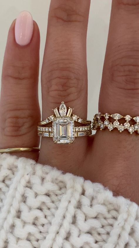 Samanthina features a striking emerald cut diamond sitting atop the band. We then sprinkled some diamonds along the ring's gallery to give it extra sparkle and a peek-a-boo halo. To add to her magnificence she exhibits pave half way down her band. Islet's curved band holds a marquise diamond as the center piece accompanied by two baguette cuts on either side with round cut sparklers finishing off the piece. Iva is the perfect companion that effortlessly stacks to create a harmonious and elegant Curved Wedding Band With Emerald Cut Engagement Ring, Wedding Bands With Emerald Engagement Ring, Wedding Bands That Go With Emerald Cut, Three Stone Emerald Cut Engagement Ring And Wedding Band, Emerald Wedding Rings Engagement, Emerald Cut Wedding Stack, Oval Engagement Ring With Wedding Band Gold, Emerald Cut Ring With Wedding Band, Dream Engagement Rings Unique