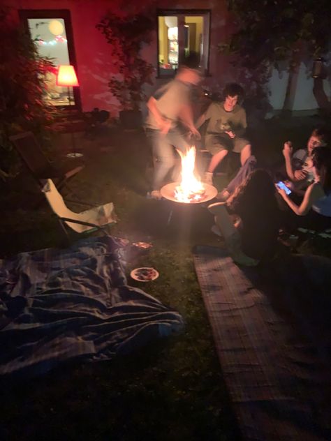 friends sitting around a fire on a late night in june, 2 picnic blankets in the foreground with an empty camping chair next to the fire Friends Driving At Night Aesthetic, Bbq Aesthetic Night, Family Barbeque Aesthetic, Potluck Aesthetic, Night Picnic Aesthetic, Late Night Party Aesthetic, Cookout Aesthetic, Late Night Picnic, Sahara Movie