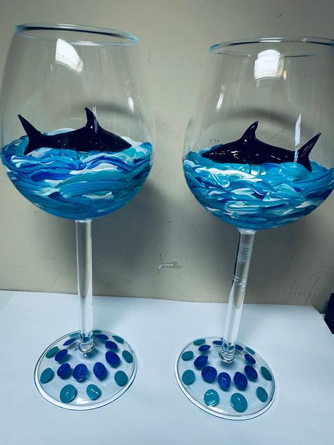 Hand Painted Stemmed Shark Wine Glasses with 3D Black Glass stemmed Shark inside surrounded by hand painted blue ocean. Each special glass is individually painted in similarity.  Great for any occasion, plus a beautiful decorative piece, giving you joy to your wine drinking experience. Use for Red, White, Rose or favorite drink for a touch of shark excitement. A one-of-a-kind gift for any occasion. Customized Requests are excepted using your favorite colors. Glass Shark available in clear, black, or pink. Dishwasher safe but NOT recommended. Handle with care, recommend gentle hand washing only. Glass Jar Painting Ideas Cute Easy, Easy Wine Glass Painting Ideas, Painted Shot Glasses Diy, Beer Glass Painting, Wine Glass Painting Ideas Easy, Glass Cup Painting Ideas, Pink Dishwasher, Paint Wine Glasses, Wine Glass Painting Ideas