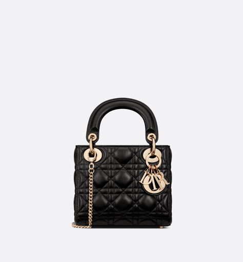 The Lady Dior bag epitomizes the House's vision of elegance and beauty. Refined and sleek, the timeless creation is crafted in black lambskin and covered with Cannage stitching, creating an instantly recognizable quilted texture. The pale gold-finish metal D.I.O.R. charms embellish and illuminate its silhouette. Featuring a removable chain shoulder strap, the miniature Lady Dior bag can be carried by hand or worn crossbody as an ideal evening wear companion. Lady Dior Bag Black, Miss Dior Bag, Dior Mini Bag, Lady Dior Mini, Mini Lady Dior, Lady Dior Handbag, Tas Fashion, Womens Designer Bags, Christian Dior Couture