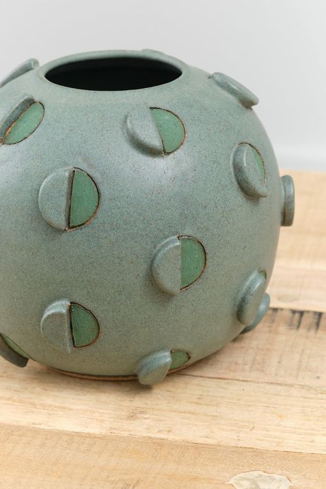 The Barrel Cactus Vase is a large decorative and functional bulbous vase with an abstract circle design throughout in a rich green glaze. Hand-carved and hand-painted geometric and three dimensional circle details adorn the exterior of the vase, finished with a Matthew Ward signature at the base. Ceramic Trends 2024, Ceramic Urns For Ashes, Ceramic Carving Designs, Ceramic Vase Ideas, Abstract Vases, Geometric Pottery, Sculptural Vases, Pottery Abstract, Modern Ceramics Design