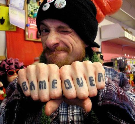 A full fingered tattoo which read game over, this can make an excellent finger tattoos idea for gamers as they too are known to be working magic with their hands. The custom font used is also has a digital 8 bit kind of effect to it, the ones used in ancient game long before computer gaming.  #tattoos #tattoofriday #tattooart #tattoodesign #fingertattooideas #smallfingertattoos  #insidefingertattooideas #fingertattoosmeaning #fingertattoosfade #fingertattoosforguy | #elegantfingertattoos Finger Tattoos For Men, Men Finger Tattoos, Finger Tattoos Fade, Inside Finger Tattoos, Knuckle Tattoo, Video Game Tattoos, Tato Jari, Gamer Tattoos, Small Finger Tattoos