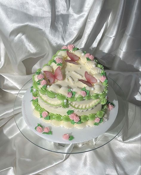 Birthday cake with white icing and pink and green piping, butterfly decorations and small flowers Sage Green Heart Cake, Butterfly Heart Cake, Vintage Fairy Cake, Garden Themed Cake, Pink And Green Birthday, Shaped Birthday Cake, 21st Bday Cake, Garden Birthday Cake, Heart Shaped Birthday Cake