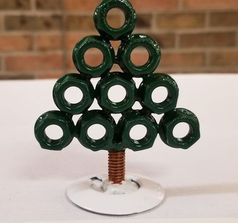 If you are needing a little desk tree to brighten the spirit at the office, we have a tree made from exhaust flange nuts, and a bit of a bolt as the trunk! Painted in evergreen, with a brown trunk, and the base painted in snow white. Clear coated for long lasting protection. There are a few of these made, and they all vary just a little bit in height but all the same materials. Dimensions: 3-3.5in tall , 2.75in wide. The base in 1.5in wide. Weighs less than 1/2 pound Nut And Bolt Art, Tool Ornaments, Nuts And Bolts Art, Metal Christmas Decor, Metal Crafts Diy, Christmas Crafts Kids Ornaments, Hardware Crafts, Metal Christmas Ornaments, Gs Swaps