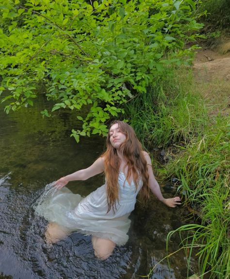 A girl in a while dress lays in the river, her dress wet surrounding her. The bank of the river is covered in grass and shrubbery. Water Nyphms, River Nymph Aesthetic, Water Nymph Photoshoot, White Dress In Water, Water Nymph Aesthetic, Tinker Bell Aesthetic, River Nymph, Bell Aesthetic, River Shoot