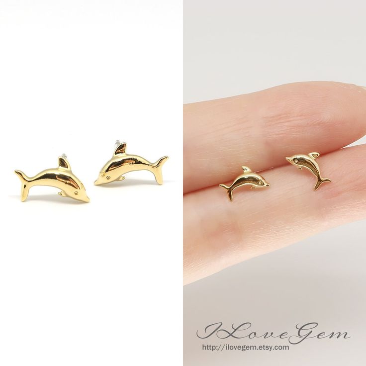 two small gold dolphin earrings sitting next to each other