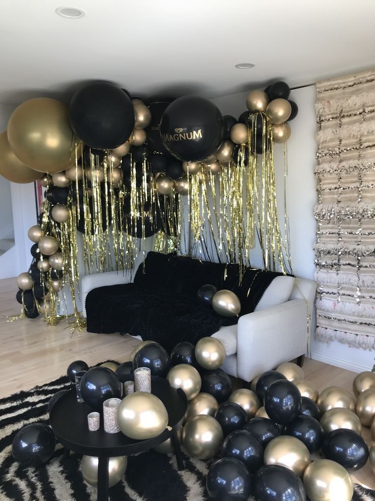 a living room filled with black and gold balloons