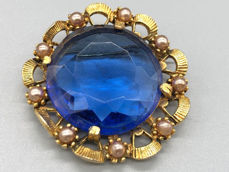 A beautiful vintage blue brooch with a faux pearl border. Approximate measurements  Length - 4.5 cm Width - 4.5 cm  * Due to this item being vintage there may be markings on the piece.  Please view the video and photos to see the condition of the jewellery. Blue Victorian Brooch For Formal Occasions, Blue Victorian Brooches For Formal Occasions, Victorian Blue Brooch For Formal Occasions, Blue Costume Jewelry Brooch For Wedding, Vintage Blue Brooch Pin, Blue Round Brooch For Formal Occasions, Formal Blue Round Brooch, Formal Blue Round Brooches, Pearl Border