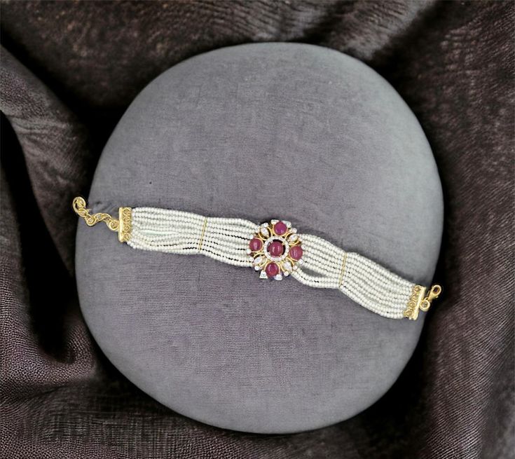 Add a touch of sophistication to your jewelry collection with this exquisite 18k gold bracelet. Featuring a stunning beaded flower design adorned with sparkling diamonds and vibrant rubies, this piece is a true work of art. The delicate pearls add an elegant finishing touch, making it perfect for special occasions or as a thoughtful gift. Each bracelet is handcrafted with meticulous attention to detail, ensuring a unique and high-quality accessory that you'll cherish for years to come. Materials: 18k gold, diamonds, rubies, pearls Design: Beaded flower with diamond and ruby accents Craftsmanship: Handmade with care and precision Occasion: Ideal for weddings, anniversaries, or as a luxurious gift Care Instructions: Store in a dry, cool place and clean with a soft cloth Make a statement with White Gold Bracelet With Round Beads For Wedding, White Temple Jewelry Bracelets, Yellow Gold Bracelets With Round Beads For Weddings, Gold Arm Band, 18k Gold Bracelet, Gold Armband, Ruby Beads, Wide Bracelet, Pearl Design