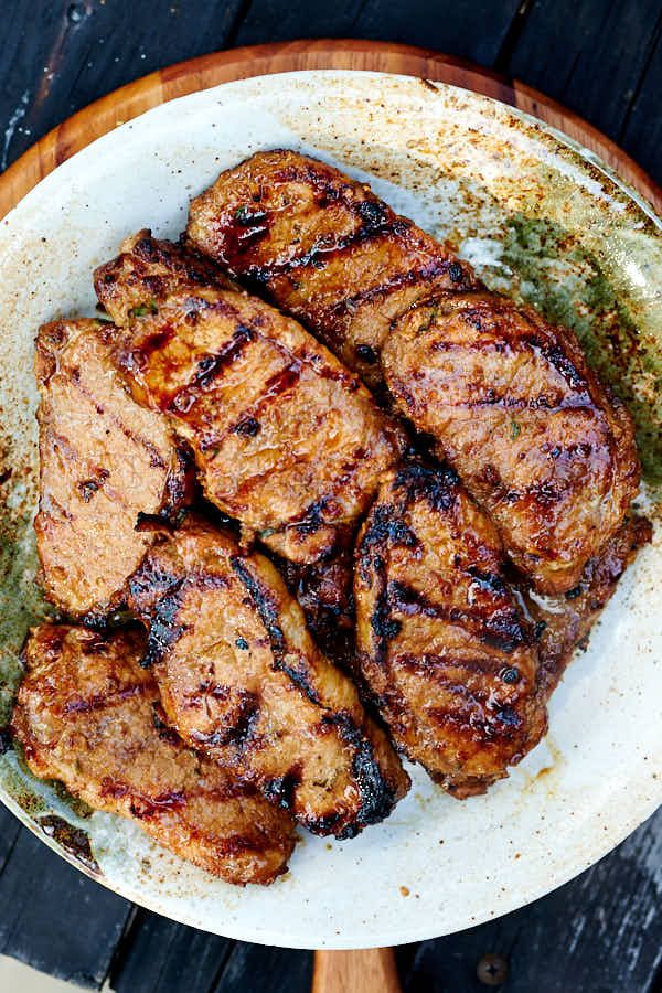 grilled meat on a white plate sitting on top of a wooden table