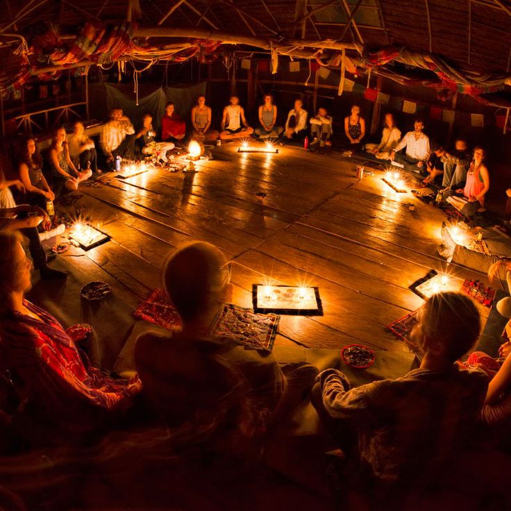 a group of people sitting in a circle on the floor with candles lit around them