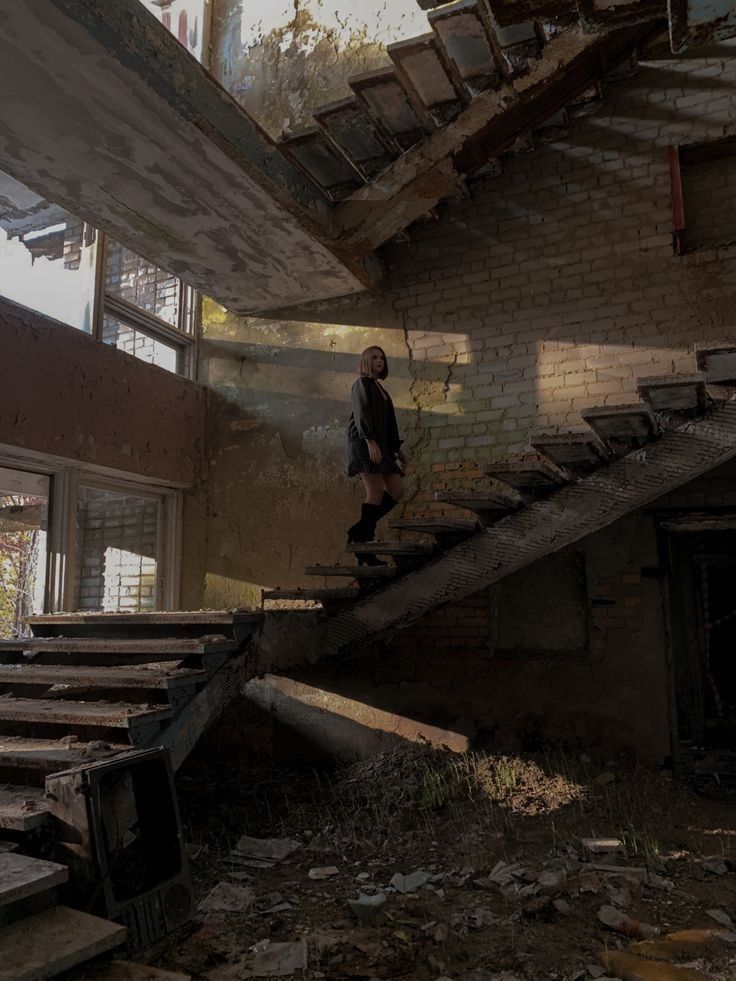 a man riding a skateboard down the side of a set of stairs in an abandoned building