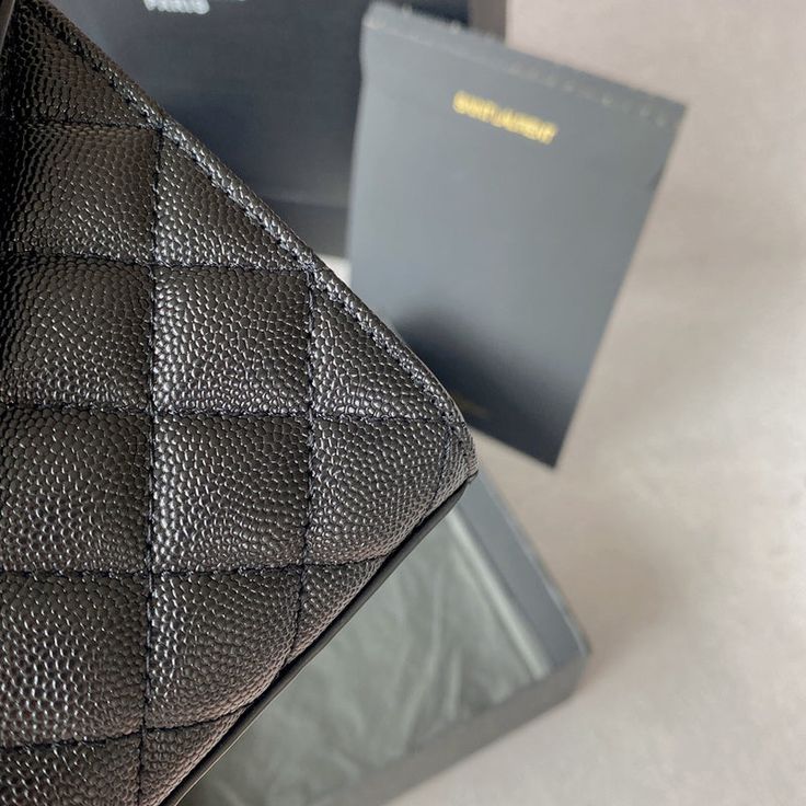 a black purse sitting on top of a table next to two other boxes and papers