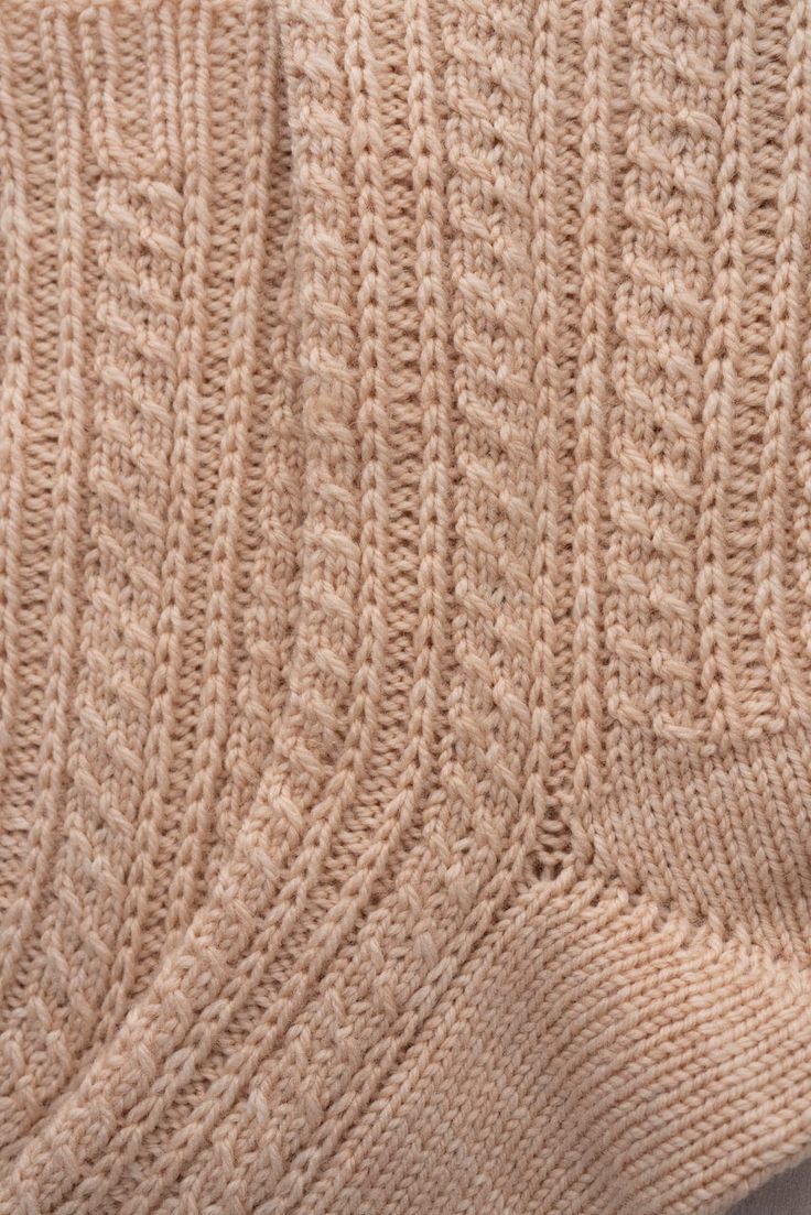 a close up view of the back of a knitted sweater with cables on it