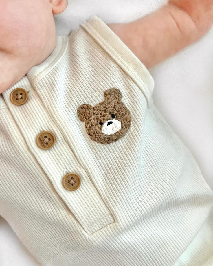 a baby is laying down with a teddy bear on it's chest