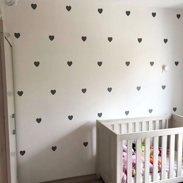 a baby's room with white walls and black hearts on the wall