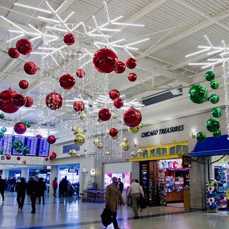 people are walking through an indoor shopping mall with christmas decorations hanging from the ceiling above them