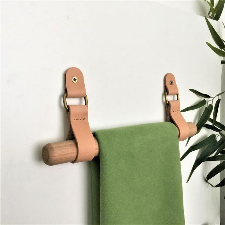 a pair of leather straps hang on the wall next to a green towel and potted plant