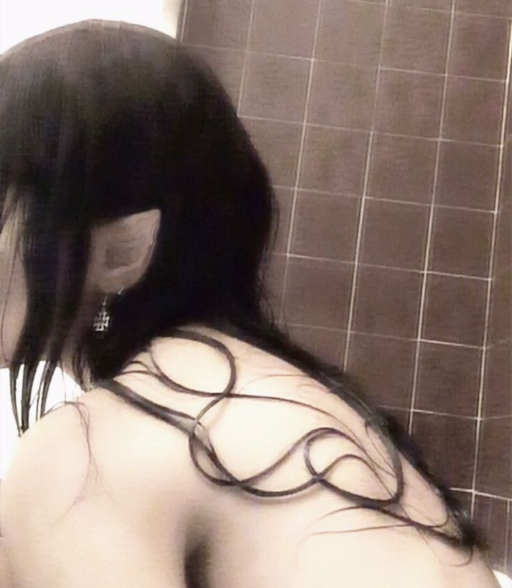 a woman with long black hair standing in front of a shower