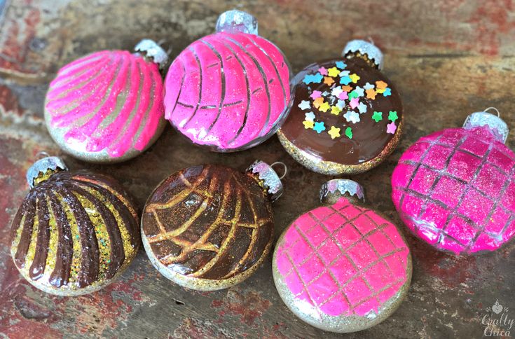 six decorated cookies sitting on top of a wooden table covered in pink and brown icing