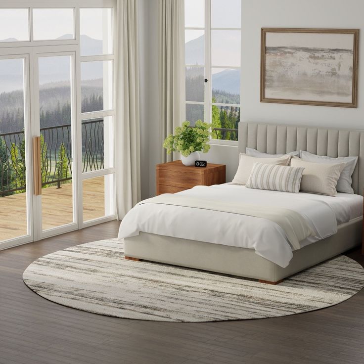 a large bed sitting in a bedroom on top of a hard wood floor next to a window