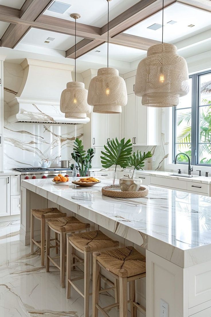 a kitchen with white cabinets and marble counter tops, hanging lights over the island area