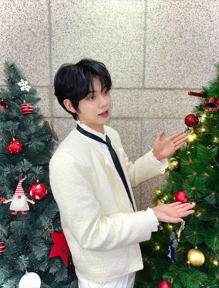 a man standing next to a christmas tree