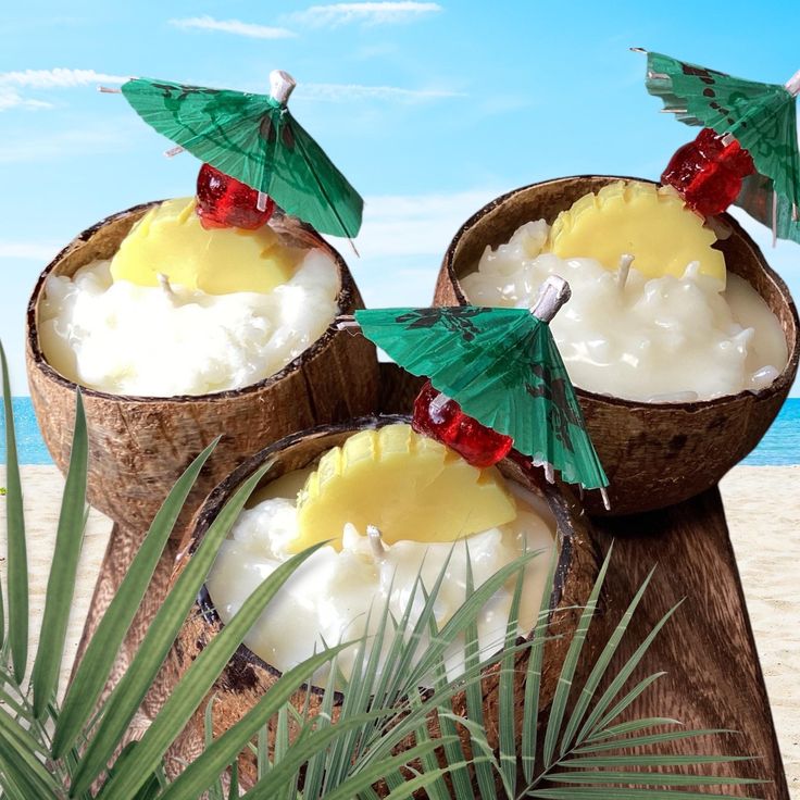 two coconuts with drinks in them on the beach